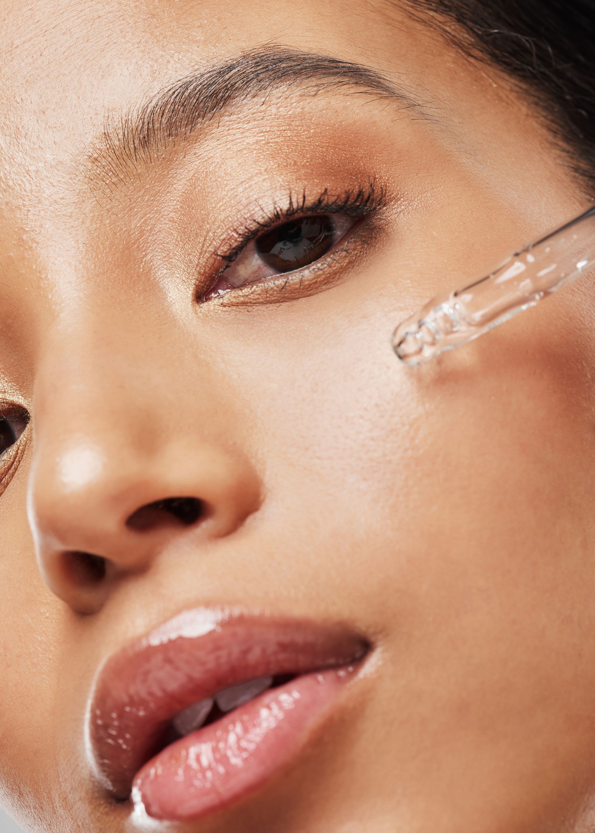 Portrait of an attractive young woman applying serum to her face